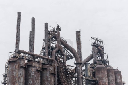 Row of rusting blast furnaces at an abandoned steel plant in winter, gray sky, horizontal aspect