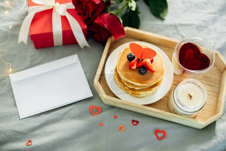 Foto de Homemade pancakes with berries, flowers and gift box. Breakfast or brunch for Valentine's Day. Mockup. Blank for greeting card for text. - Imagen libre de derechos