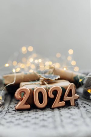 Christmas and New Year Greeting Card. Number 2024 on knitted background. Holiday lights bokeh background. Happy New Year 2024 Concept