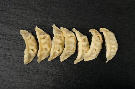 Photo for Gyoza Chinese Dumplings Row, Steamed Vegetable Jiaozi, Chicken Momo Pile, Asian Gyoza Group on Black Stone Plate Background, Copy Space - Royalty Free Image