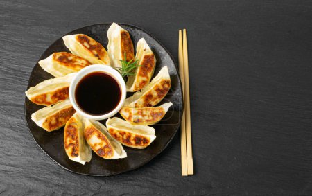 Photo for Gyoza Chinese Dumplings on Black Plate, Fried Vegetable Jiaozi, Chicken Momo Pile, Asian Gyoza Group, Stone Background, Top View, Copy Space - Royalty Free Image
