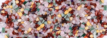 Colorful stones texture background. Green, red, blue, white, black and purple quartz pebbles mix top view