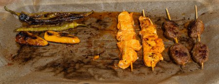Photo for Small Skewers, Street Barbecue, Chicken Shish Kebab, Barbecue Shashlik, Skewered Grilled Chicken Meat Pieces on Paper Background - Royalty Free Image
