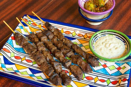 Photo for Moroccan Beef Kebab on Skewers, Traditional Arabian Food, Mutton Shashlik, Skewered Grilled Veal Meat, Spicy Lamb Grill with White Sauce - Royalty Free Image