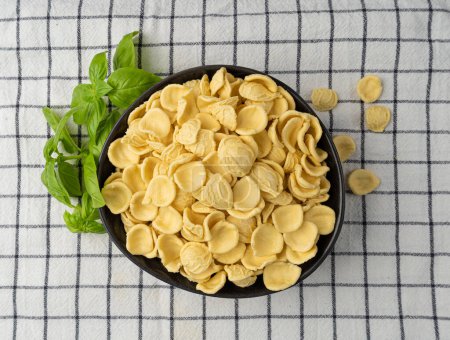Photo for Raw Orecchiette Pasta, Homemade Dry Macaroni, Italian Recchietedde, Raw Noodle, Orecchiette Pasta on Checkered Napkin Background - Royalty Free Image