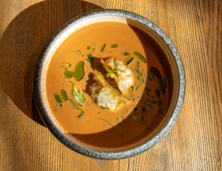 Photo for Nepalese Momo Jhol Achar Dumpling Soup, Fried Gyoza Broth, Spicy Tomato Momo Seasoned Soup in Exquisite Serving Restaurant Bowl in Sunlight Closeup - Royalty Free Image