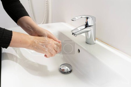 Photo for Washing hands with soap closeup. Woman wash her palms, soapy arms, washing hands on white blurred background, hygiene concept - Royalty Free Image