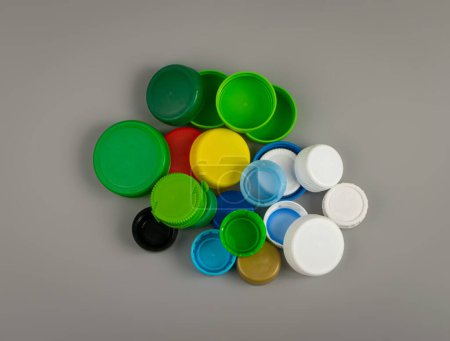 Téléchargez les photos : Bouchons de bouteille en plastique Pile. Groupe de matériaux HDPE de recyclage, Couvercle en polyéthylène, Groupe de capsules colorées sur fond gris - en image libre de droit