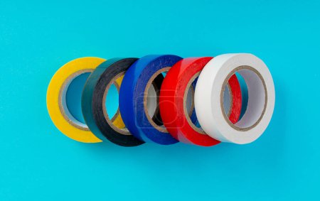 Foto de Cinta eléctrica colorida, rollos de cinta de plástico, cintas adhesivas coloreadas en el fondo azul Vista superior - Imagen libre de derechos