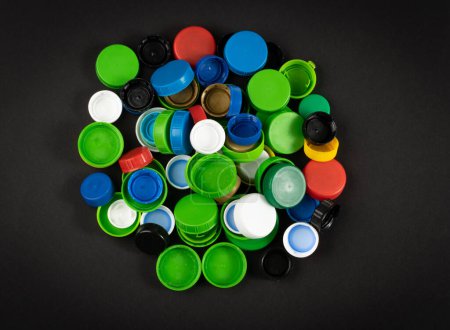 Téléchargez les photos : Bouchons de bouteille en plastique Pile. Groupe de matériaux HDPE de recyclage, Couvercle en polyéthylène, Groupe de capsules colorées sur fond noir - en image libre de droit