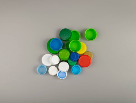Téléchargez les photos : Bouchons de bouteille en plastique Pile. Groupe de matériaux HDPE de recyclage, Couvercle en polyéthylène, Groupe de capsules colorées sur fond gris - en image libre de droit