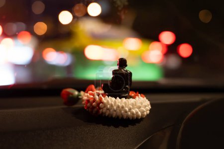 Rückansicht der kleinen Buddha-Statue auf der Jasmingirlande an der Front des Autos. Bokeh Licht Hintergrund in der Nacht.