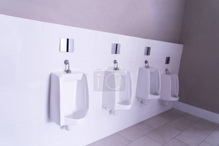 Public restroom. Row of urinals. The urinal design is white ceramic. Modern men's bathroom.