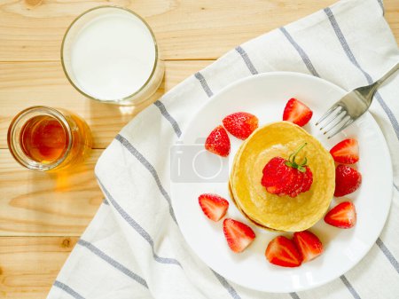 Stapel hausgemachter Mehlflocken-Pfannkuchen mit frischen Erdbeeren und Honig
