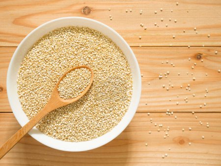 Photo for A bowl of uncooked white quinoa on wooden table. Top view. - Royalty Free Image