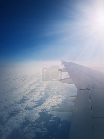 Photo for Plane flight above the clouds. Blue skyline and airplane wing seen through the windo - Royalty Free Image
