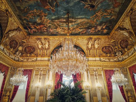 Téléchargez les photos : Beaux appartements Napoléon décorés au palais du Louvre. Chambres familiales royales avec rideaux rouges cardinaux, murs ornés d'or, peintures et lustres en cristal suspendus au plafond - en image libre de droit