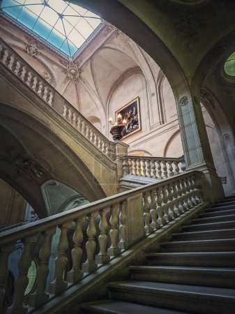 Foto de Palacio del Louvre detalles arquitectónicos de una sala con escalera de piedra, barandillas adornadas y lámparas vintage brillantes, París, Francia - Imagen libre de derechos