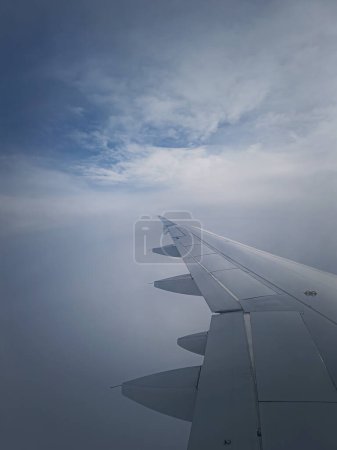 Téléchargez les photos : Vol en avion à travers les nuages brumeux denses, plan vertical. Aile d'avion vue à travers le windo - en image libre de droit