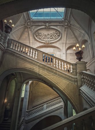 Foto de Palacio del Louvre detalles arquitectónicos de una sala con escalera de piedra, barandillas adornadas y lámparas vintage brillantes, París, Francia - Imagen libre de derechos