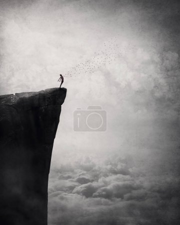 Freedom and liberty conceptual scene. Man on the edge of a cliff self liberating from fears and doubts as a flock of birds escape his body and fly free in the air. Surreal and inspirational art