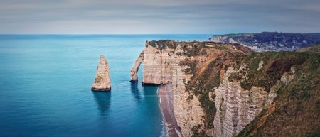 Téléchargez les photos : Vue panoramique sur la célèbre Aiguille rocheuse d'Etretat en Normandie, France. Falaises calcaires Falaise d'Aval baignées par les eaux du chenal de La Manche. Beau panorama du littoral - en image libre de droit