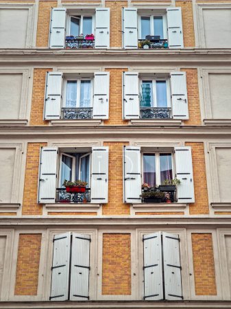 Téléchargez les photos : Façade du bâtiment avec murs de maçonnerie de briques peints en jaune et fenêtres avec volets extérieurs blancs - en image libre de droit