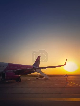 Photo for Airplane ready for boarding and takeoff at the airport with the view to the sunrise. Morning travel and holiday concept - Royalty Free Image