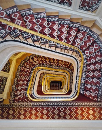 Foto de Forma abstracta escaleras de lujo con cubierta de alfombra roja y pasamanos de oro. Escalera espiral patrón hipnótico - Imagen libre de derechos