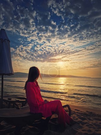 Téléchargez les photos : Femme se détendre sur le transat que rencontre l'aube à la plage. Belle scène de lever de soleil de mer, vacances d'été bord de mer, Voyage et vacances concept de détente - en image libre de droit