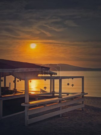Photo for Early morning seaside next to beach bar with a beautiful view to the sunrise over the sea. Vacation and relax concept - Royalty Free Image