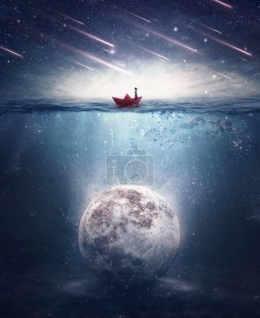 Garçon naviguant dans un bateau en papier à la recherche de la lune coulée sous l'eau. Satellite noyé dans l'eau de l'océan dans une nuit mystérieuse avec des étoiles tombantes. Contexte surréaliste, concept d'aventure mystique