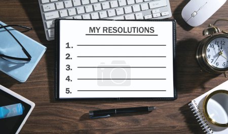 Photo pour Ma liste de résolutions sur le bloc-notes avec des objets d'affaires. - image libre de droit