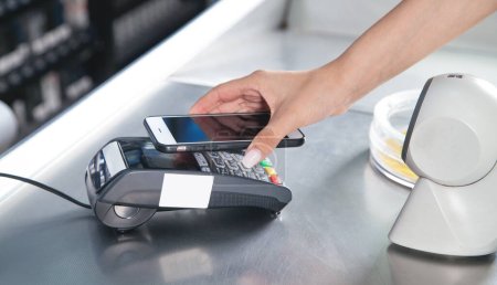 Photo for Customer paying for purchases contactless with smartphone. - Royalty Free Image