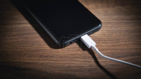 Smartphone charging battery on the wooden table.