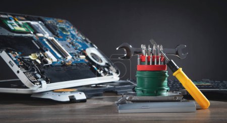 Photo for Broken laptop with a wrench and screwdriver on the table. Computer repair service - Royalty Free Image
