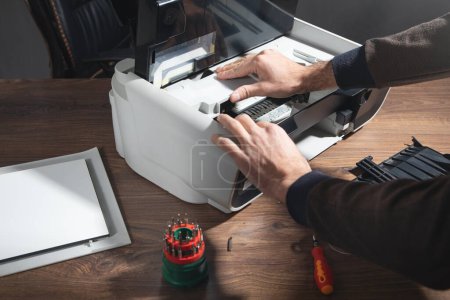 Photo for Caucasian man repairing digital printer. - Royalty Free Image