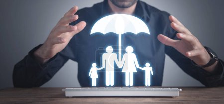 Téléchargez les photos : Homme protéger le symbole de la famille avec un parapluie. Concept d'assurance familiale - en image libre de droit