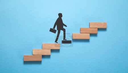 Foto de Empresario escalando en escalera de carrera hecha por bloque de madera. Desarrollo personal. Crecimiento de carrera - Imagen libre de derechos