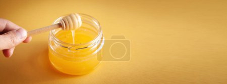 Téléchargez les photos : Pince à main mâle et pot de miel sur fond jaune. - en image libre de droit