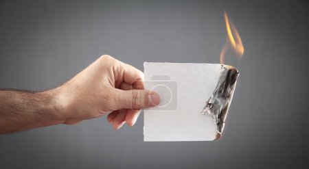 Male hand holding white burned paper.