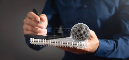 Téléchargez les photos : Journaliste caucasien tenant microphone, bloc-notes et stylo. - en image libre de droit