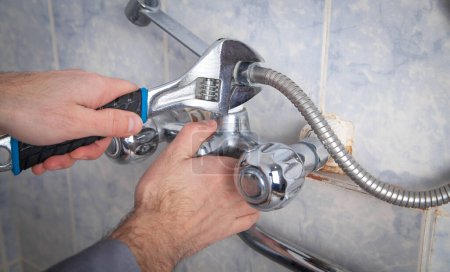Téléchargez les photos : Robinet de douche de réparation et de fixation d'homme dans la salle de bain. - en image libre de droit