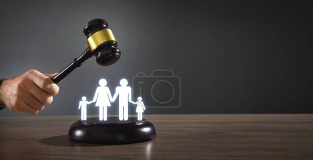 Männliche Hand hält Richtergabel mit einem Familiensymbol. Familienrecht