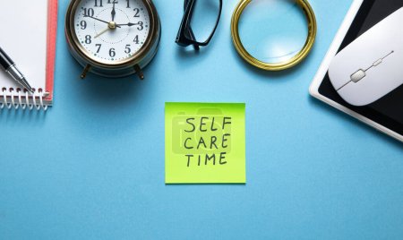 Photo for Self care time on sticky note with a clock and business objects. - Royalty Free Image