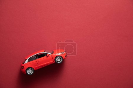 Red toy car on the bordeaux background.