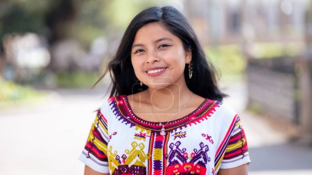 Porträt einer schönen jungen indigenen Frau in einem farbenfrohen Kleid aus dem Quich.