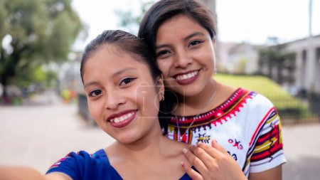 Foto de Portrait of two friends taking a selfie with the cell phone in the park of Quetzaltenango. - Imagen libre de derechos