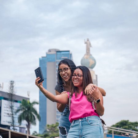 Photo for Best friends on vacation in San Salvador, girls taking selfie on mobile phone - Royalty Free Image