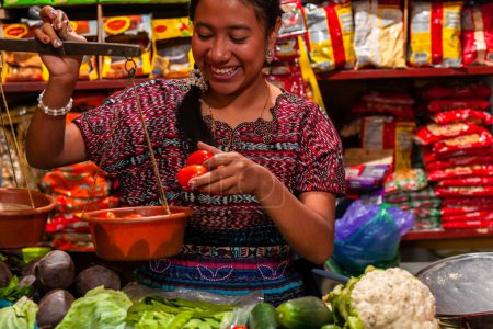 Téléchargez les photos : Femme souriante heureuse mettre des tomates à l'échelle, bazar alimentaire au Guatemala - en image libre de droit